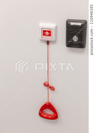 A red emergency pull cord system on a white wall in a clinical setting. 110946385