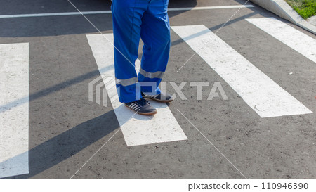 Partial view of a paramedic in uniform standing on a zebra crossing, focus on feet 110946390