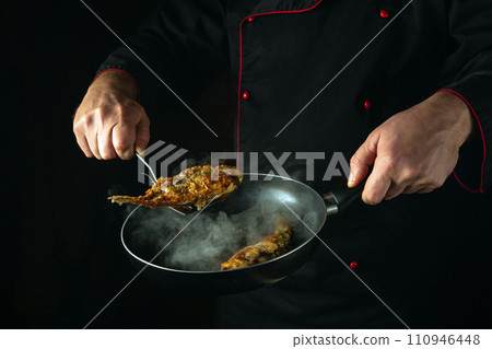 A professional chef prepares fish in a restaurant or hotel kitchen. Fry the crucian carp in a hot frying pan. Idea for a delicious fish diet A professional chef prepares fish in a restaurant or hotel kitchen. Fry the crucian carp in a hot frying pan. Idea for a delicious fish diet 110946448