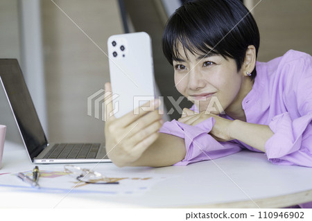 Young woman having a video call with her boyfriend on her smartphone while working remotely at home 110946902