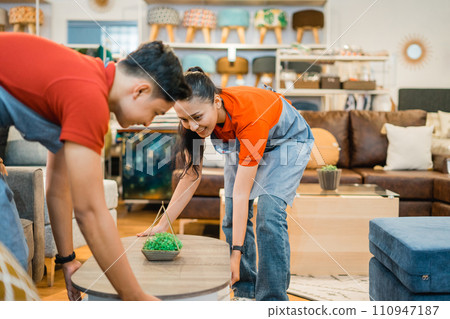 two Asian shop assistants in aprons move a table together while working 110947187