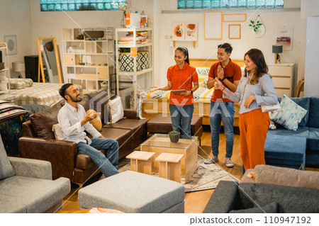 customer trying to sit on sofa with his wife with shop waiters 110947192