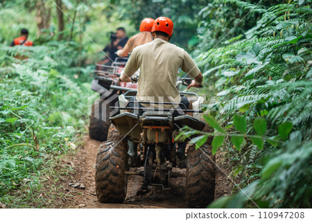 the back of asian man that riding the atv through the track 110947208