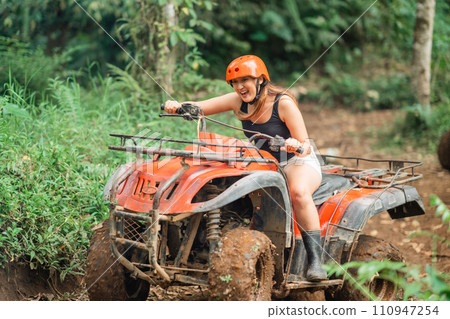 excited asian woman screaming while riding the atv through the difficult way 110947254
