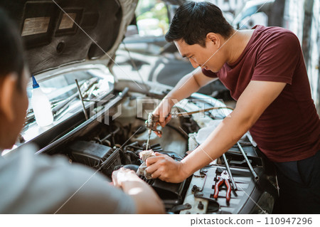 male mechanic cleans an air filter duct using an air duster gun 110947296