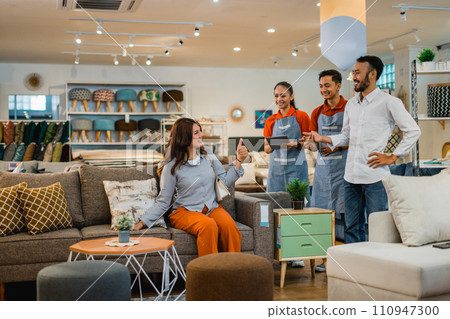 customer enjoys trying to sit on a sofa while two waiters serve 110947300