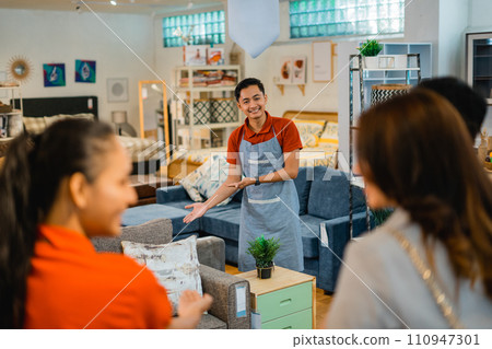 shop assistant man invites customers to see furniture products shop assistant man invites customers to see furniture products 110947301