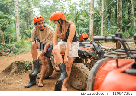 young asian couple wearing the boots before riding an atv 110947392