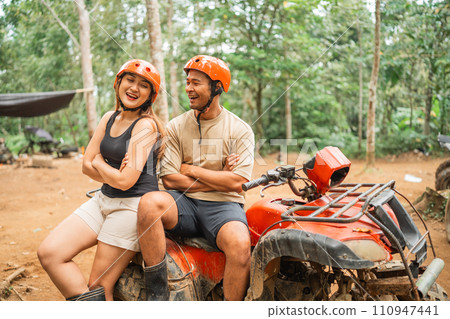 happy asian couple sitting on the atv with handcrossed 110947441
