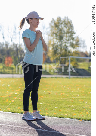 A young beautiful woman in sportswear plays sports at a local stadium. Exercise, jog and exercise at the beginning of the day. Healthy and active lifestyle. 110947442