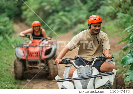 handsome asian man overtaking his partner atv through the atv track handsome asian man overtaking his partner atv through the atv track 110947473