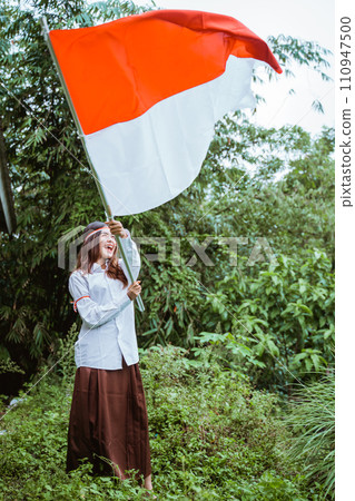 a beautiful asian woman in white shirt standing wave the flag pole a beautiful asian woman in white shirt standing wave the flag pole 110947500