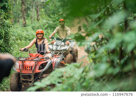 happy asian couple riding the atv together spending their holiday happy asian couple riding the atv together spending their holiday 110947676
