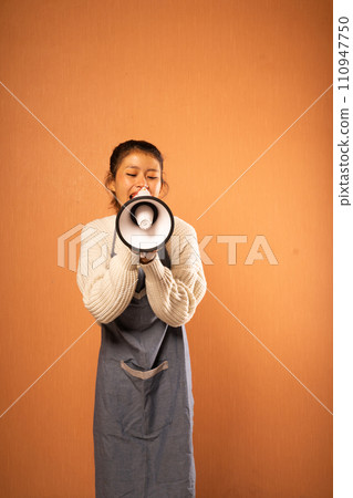 Asian woman wearing apron announcing with megaphone in isolated background Asian woman wearing apron announcing with megaphone in isolated background 110947750