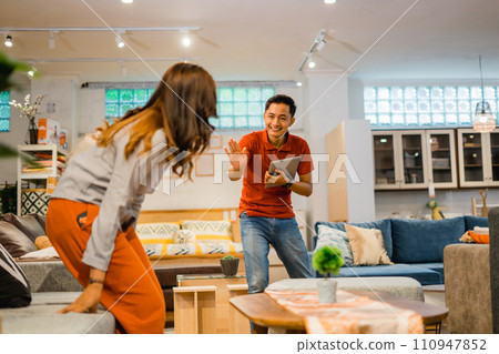 male store employee with hand gesture forbids visitor sitting on sofa male store employee with hand gesture forbids visitor sitting on sofa 110947852