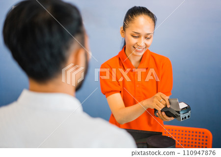 woman shop assistant swiping credit card on EDC device as shoppers pay 110947876