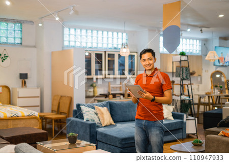 smiling Asian male store owner using a tablet in furniture store smiling Asian male store owner using a tablet in furniture store 110947933