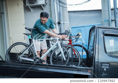 young man unlocks a bicycle while picking up in a pickup truck young man unlocks a bicycle while picking up in a pickup truck 110947982