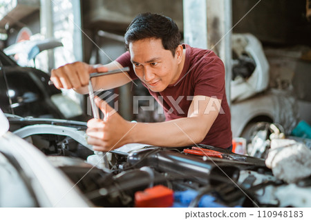 car mechanic using T socket to car engines parts for fixing 110948183