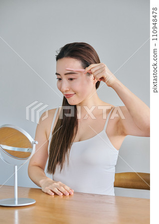 A woman in her 30s shaving her face with a ladies razor 110948478