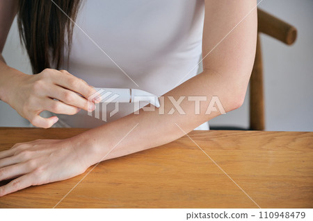 A woman in her 30s shaving her arm hair with an electric shaver A woman in her 30s shaving her arm hair with an electric shaver 110948479