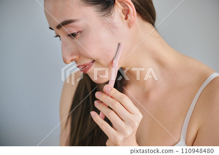A woman in her 30s shaving her face with a ladies razor A woman in her 30s shaving her face with a ladies razor 110948480