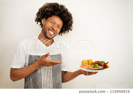 black man holds plate of salmon in modern kitchen 110948658