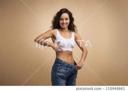 Happy attractive brunette slender millennial woman wearing huge jeans 110948661