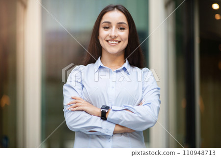 Confident arab young professional woman with long hair and blue shirt, standing with arms crossed Confident arab young professional woman with long hair and blue shirt, standing with arms crossed 110948713
