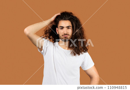 man with long hair looking puzzled against beige backdrop man with long hair looking puzzled against beige backdrop 110948815