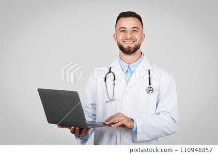 Male doctor with laptop smiling, healthcare concept. 110948857