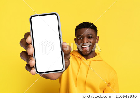 Happy young black guy showing big phone with blank screen 110948930