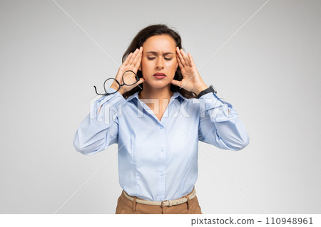 Despaired millennial caucasian lady, with pained expression, clutching at temples 110948961