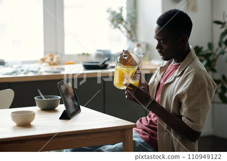 Man pouting juice and watching video Man pouting juice and watching video 110949122