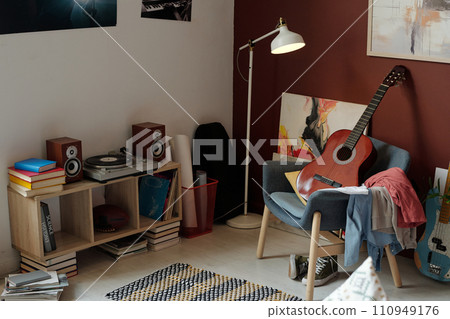 New acoustic guitar standing on armchair 110949176