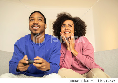 African spouses engrossed in digital video game using gamepads indoor African spouses engrossed in digital video game using gamepads indoor 110949236