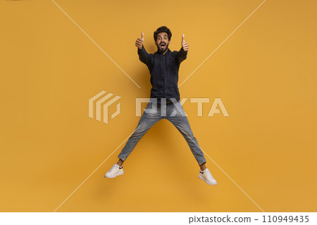 Joyful Indian Man Jumping In Air And Showing Thumbs Up At Camera 110949435
