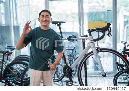 young asian man smiling with okay hand gesture while holding wrench 110949437