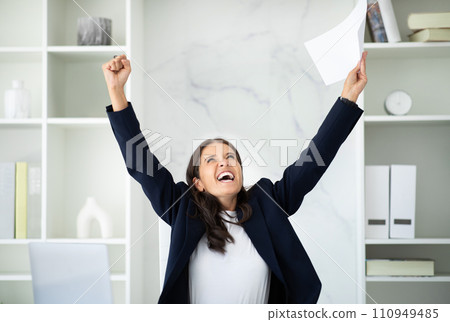 Happy mature woman manager raising hands up, office interior 110949485