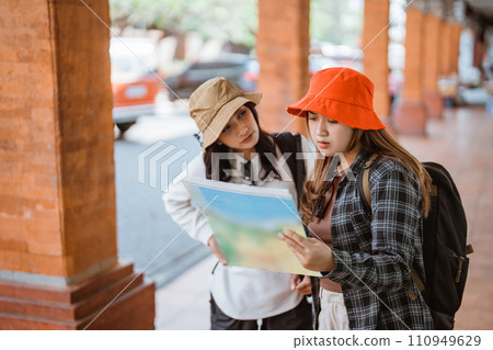 two attractive girls look at a map getting to a tourist destination 110949629