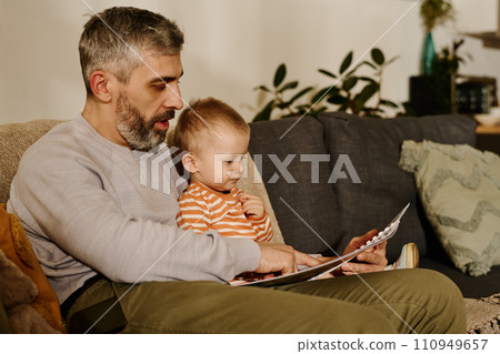 Mature father reading comics to son Mature father reading comics to son 110949657