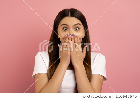 Surprised teen girl covering mouth with hands and looking at camera Surprised teen girl covering mouth with hands and looking at camera 110949679