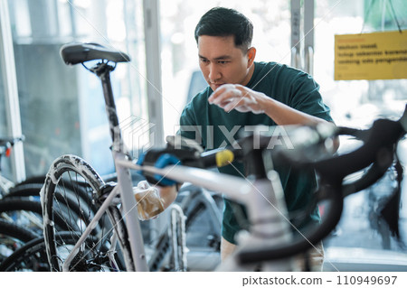 young man cleaning bicycle with foaming soap with indoor background young man cleaning bicycle with foaming soap with indoor background 110949697