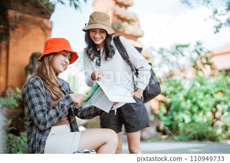two Asian female tourists observe the map of the tourist destination 110949733