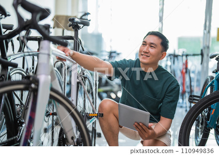 young male employee using a tablet while checking a bicycle frame young male employee using a tablet while checking a bicycle frame 110949836