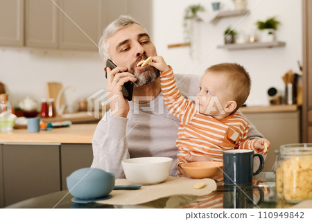Boy putting biscuits into father mouth Boy putting biscuits into father mouth 110949842