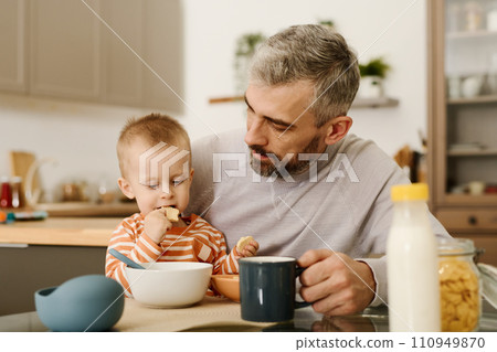 Father looking at baby son with cookies Father looking at baby son with cookies 110949870