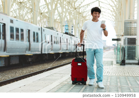 Asian guy traveler using smartphone, standing by train Asian guy traveler using smartphone, standing by train 110949958