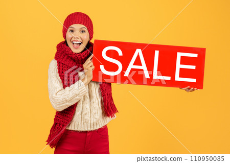 woman in winter clothes holding Sale sign on yellow backdrop woman in winter clothes holding Sale sign on yellow backdrop 110950085