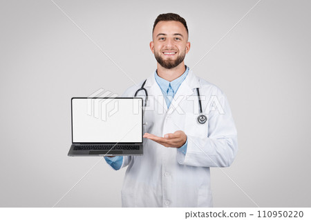 Happy male doctor showcasing a laptop with a blank screen Happy male doctor showcasing a laptop with a blank screen 110950220